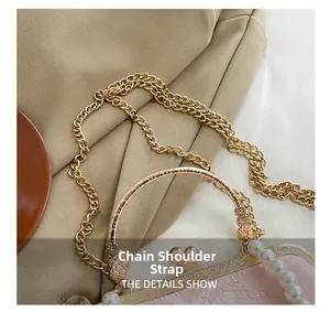Detail of light gold chain strap and embossed floral handle with white pearls on pink bag