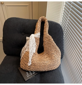 Detail of hand-woven straw hobo bag with elegant white lace ribbon on a chair