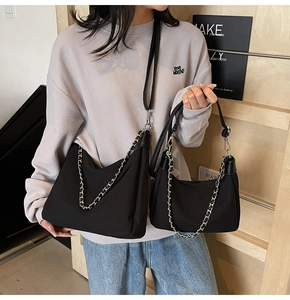 Detail of minimalist black crossbody bags featuring silver chain and leather corners