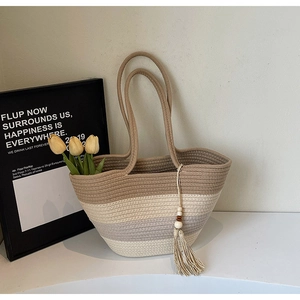 Detail view of woven straw tote bag with gradient stripes and wooden bead tassel decor