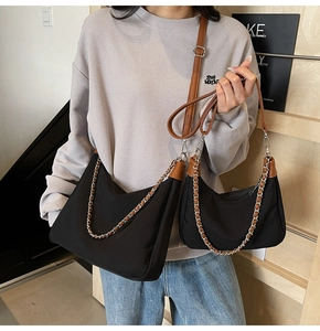 Close-up of contrast leather trim and chunky chain on black nylon shoulder bags