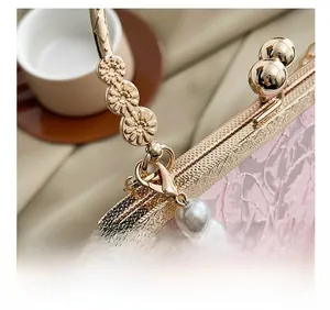 Close-up of pink lace fabric with gold floral carved metal frame and sphere clasp