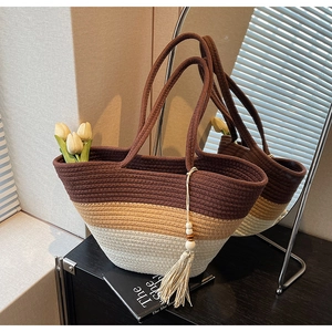 Detail of a woven gradient straw tote bag with elegant tassels and wooden bead accents