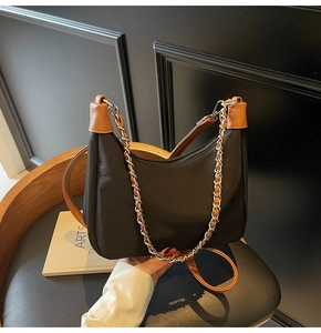 Close-up of black nylon shoulder bag featuring brown leather trim and silver chain strap
