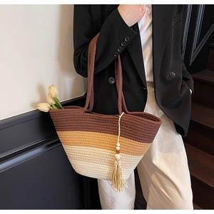 Detailed weave texture of gradient straw tote bag with decorative tassel and wooden beads