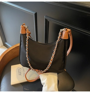 Detail of black nylon crescent bag with brown leather trim and dual strap options