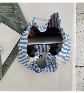 Detail view of large blue striped canvas tote bag showing interior space for laptop and items
