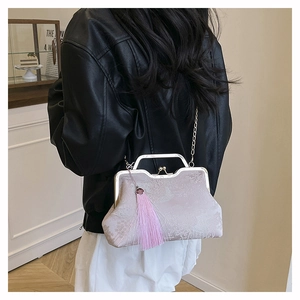 Detail view of retro floral embroidery bag with metal clasp and pink tassel accent