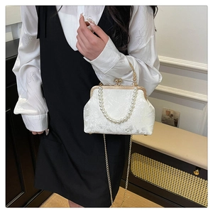 Detail of white jacquard evening bag with pearl handle and vintage metal clasp