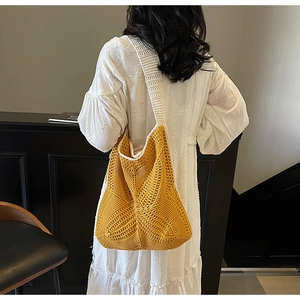 Detail of the yellow hollow-out crochet pattern and soft knit texture of the hobo bag