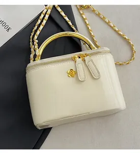 Detail of cream white vanity case bag with gold metal handle and chain strap