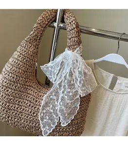 Brown woven tote bag detail featuring white lace scarf and dense straw texture