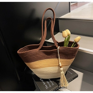 Detail of woven straw tote bag with gradient color blocks and wood bead tassel decoration