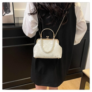 Detailed view of vintage white pearl handbag with jacquard fabric and gold chain strap