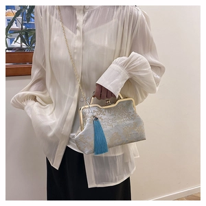 Detailed view of pale cyan satin handbag with gold floral embroidery and blue tassel