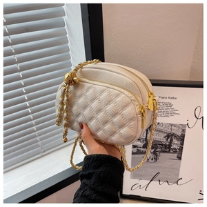 Detail of white quilted leather camera bag with dual zippers and gold chain strap