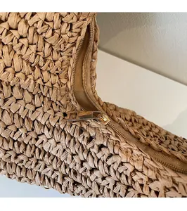 Close-up of golden zipper puller and tight woven texture on khaki shoulder bag