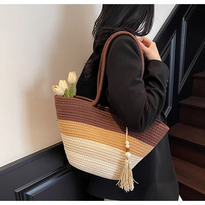 Detail of woven straw tote bag with color-block design and stylish tassel charm