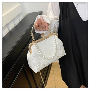 Detail of white jacquard handbag with pearl handle and vintage gold metal clasp