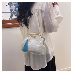 Detail of blue floral brocade handbag featuring golden frame handle and silk tassel