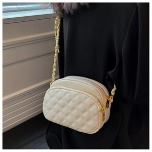 Detailed close-up of a white quilted crossbody bag with gold chain and lychee texture