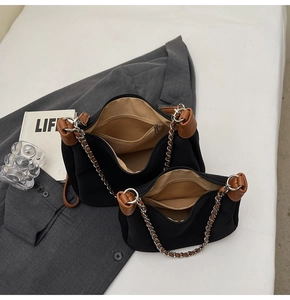 Detail view of large and small black shoulder bags with brown leather trim and silver chains