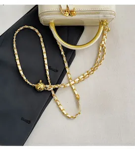 Detailed close-up of glossy cream crossbody bag with gold chain and adjustable metal ball