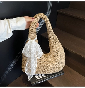 Detail of hobo straw bag with dense woven texture and decorative white lace bow