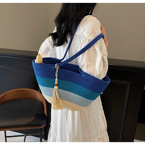 Detail of blue gradient straw tote bag with tassel and woven handle on white dress