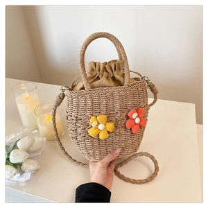Close-up of a hand-woven bucket bag featuring dual 3D fabric flowers and drawstring liner