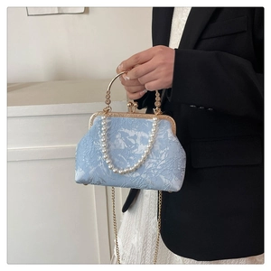 Detail of light blue floral texture bag with pearl handle and golden chain strap