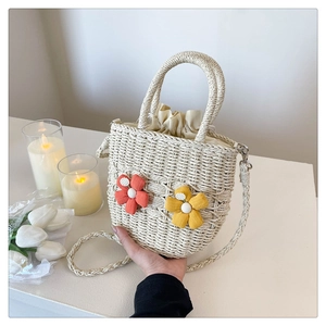 Detailed shot of beige woven bucket bag with floral accents and drawstring liner