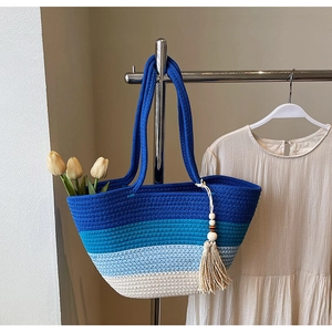Detail of blue gradient woven straw tote with boho tassel and round handles