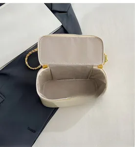 Interior detail of beige square bag showing the spacious lining and metal chain strap