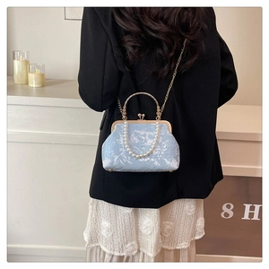 Detail of light blue jacquard pearl handbag with vintage gold metal frame and chain strap