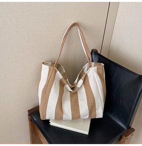Detailed view of large canvas tote bag with brown and cream stripes on a leather chair