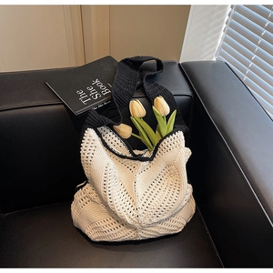 Detail of hollow knit tote bag in black and white with flowers on leather background