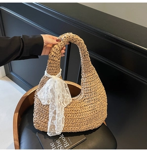 Detail of hand-woven straw tote bag with white lace bow decoration and sturdy handle