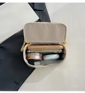 Internal view of beige mini crossbody bag showing storage for phones and makeup