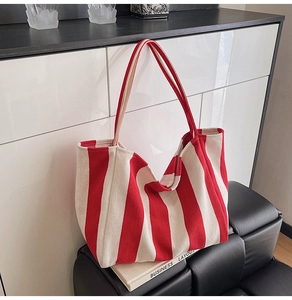 Detailed view of red and white striped canvas bucket bag on a black bench interior