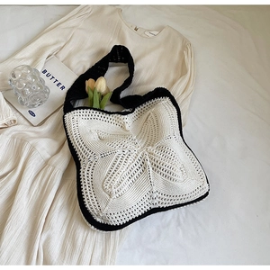 Detail of hand-crocheted shoulder bag with cream knit texture and black strap accents