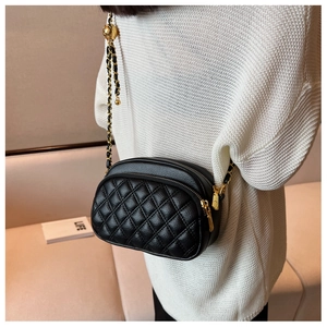 Detail of black quilted leather camera bag featuring gold ball chain and dual zippers