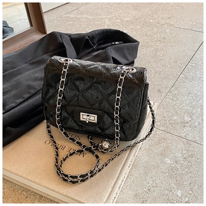 Détail de la texture cuir noir brillant matelassé et de la chaîne argentée du sac