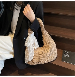 Detail of hobo straw bag featuring a large white lace bow and natural woven texture