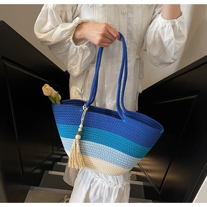 Close-up of blue gradient woven straw tote bag with wood bead tassels and white fringe