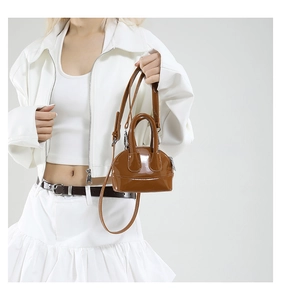 Détail du mini sac coquillage en cuir verni marron avec bandoulière réglable