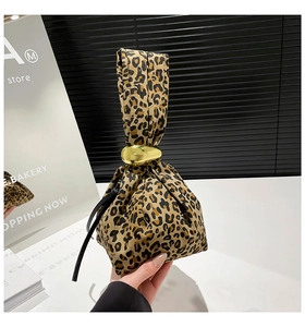 Detail of leopard print handbag with a glossy gold spherical metal clasp and knot design