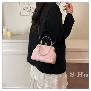 Detailed view of pink jacquard evening bag with pearl handle and metal clasp closure
