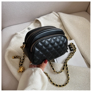 Detail of black quilted leather crossbody bag with dual zippers and gold chain strap