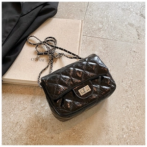 Détail du sac en cuir verni noir matelassé avec fermoir argenté et bandoulière